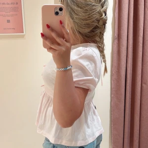 Ljusrosa blus med knyt och puffärm - Supersöt ljusrosa blus från Gina med tre knyt framtill och puffiga korta ärmar. Blusen har en lös passform och är tillverkad i mjuk bomull. Perfekt för en söt och avslappnad look. Det är barnstorlek 158/164 men passar mig som är storlek S i vanliga fall🩵💕 Knappt använd