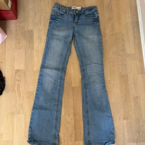 Bootcut jeans från One Collection - Ljusblå bootcut jeans från One Collection med snygga orangea sömmar på bakfickorna. Klassisk femficksmodell i jeansmaterial med normal passform och dragkedja. Perfekta för dig som gillar en retro vibe och vill sticka ut lite extra. Skit snygga, lägger ut igen! Storlek 25!🩷