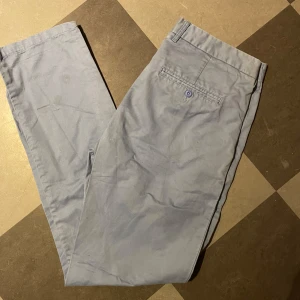 Ljusblå kostym byxor - Snygga ljusblå chinos med klassisk rak passform och bakficka med knapp. Byxorna har bälteshällor och är tillverkade i mjuk bomull, tecken på användning men går säkert bort i tvätten