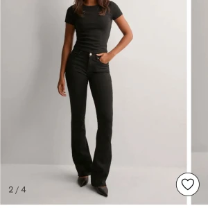 Svarta bootcut jeans med medelhög midja  - Snygga svarta jeans med bootcut och medelhög midja. Jeansen har klassisk femficksdesign och sitter tajt upptill med utsvängda ben. Perfekta för dig som gillar en stilren och trendig look.