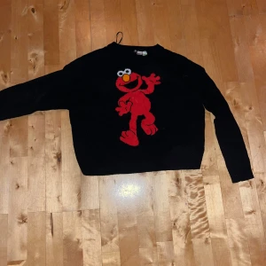 Svart stickad tröja - Svart stickad långtröja med stor röd Elmo figur. Baksidan är helt svart