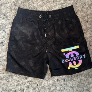 Svarta Burberry badshorts med logga - Burberry Badbyxor – Svart 🩳 Storlek: M 🖤 Färg: Svart 🔄 Skick: 8/10 – fint skick, använd men välbevarade 💎 Märke: Burberry