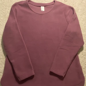 Ljuslila fleece tröja i storlek 42 - Mysig ljuslila fleece tröja med rund halsringning och långa ärmar. Perfekt för kyliga dagar och enkel att matcha med jeans eller leggings. Tröjan har en avslappnad passform och är superbekväm att bära.
