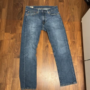 Levi's 501 blå jeans straight fit - Klassiska blå Levi's 501 jeans med rak passform och fem fickor. Jeansen har knappgylf, tydliga sömmar och den ikoniska läderpatchen bak i midjan. Tillverkade i slitstarkt denimtyg som ger en tidlös look.      L30