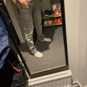 Grå slitna jeans från Jack & Jones - Säljer ett par grå jeans från Jack & Jones med slitningar och hål på låret och knät. Jeansen har fem fickor, normal passform och klassisk knappgylf. Perfekta för dig som gillar en avslappnad och trendig look.
