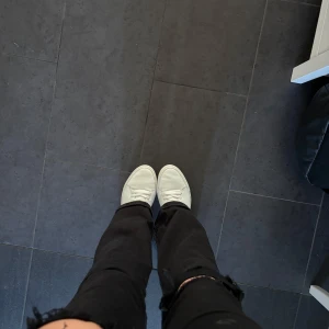 Vita sneakers från Difficult by P. - Säljer ett par stilrena vita sneakers från Difficult by P. Skorna har klassisk design med rund tå, snörning och platt sula. Tillverkade i slätt skinn med diskret guldfärgad logga på hälen. Perfekta för dig som gillar minimalistisk och clean stil. Nästa aldrig andvända!!!