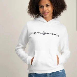 Vit hoodie från Sail Racing - Vit hoodie från Sail Racing med svart logotyptryck över bröstet. Klassisk huva och känguruficka framtill. Mjuk och skön känsla, perfekt för en avslappnad stil. Passar till jeans eller träningsbyxor.