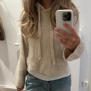 Beige stickad Zara hoodie - Mysig beige stickad hoodie från zara med croppad passform och långa ärmar. Tröjan har huva med dragsko och bred ribbad mudd vid ärmslut och nederkant. Storlek S.