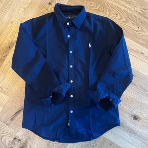 Ralph lauren skjorta - Mörkblå Skjorta från Ralph Lauren. Skjortan är i perfekt skick och passar utmärkt till det mesta. Kostar ca 1900 kr nypris, mitt pris: 650 kr. Det är strl S men passar från ca 168-178 cm. Självklart äkta✅