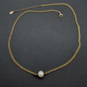 Guldfärgat halsband med pärla - Stilrent halsband i guldfärgad kedja med en rund vit pärla som hänger i mitten. Längd-44cm +5cm