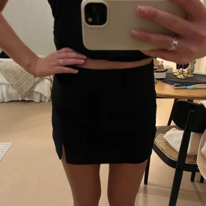 Svart minikjol från Stradivarius - Svart minikjol från Stradivarius i klassisk modell med liten slits framtill. Storlek 36!