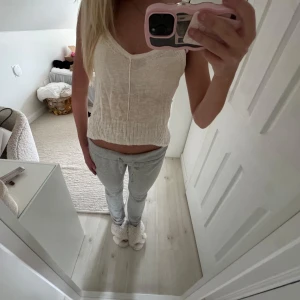 Beige stickad linnetopp med v-ringning - Säljer en ljusbeige stickad linnetopp med v-ringning och breda axelband. Toppen har en ribbad kant nertill och en dekorativ söm framtill. Perfekt för sommardagar och enkel att matcha med jeans eller kjol.