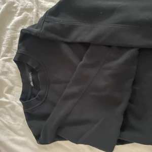 Svart sweatshirt från Zara - En stilren svart sweatshirt från Zara med rund halsringning och långa ärmar. Tröjan har en klassisk passform och är tillverkad i mjuk bomullsblandning, perfekt för en chill och enkel look. I storlek M men känns som en XS. Har kommit till användning men har tröttnat på den nu