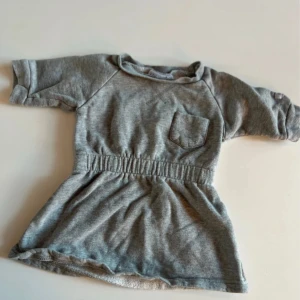 Grå kort klänning från Ebbe, stl 70 - Supermjuk grå klänning från Ebbe i sweatshirtmaterial. Modellen har resår i midjan och en liten bröstficka.