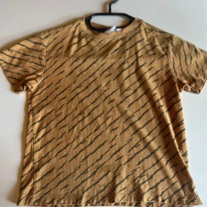 Orange t-shirt med zebramönster från Zara - Cool orange t-shirt från Zara med svart zebramönster över hela plagget. Klassisk rund halsringning och korta ärmar. Tillverkad i mjuk bomull som är skön att ha på sig hela dagen.