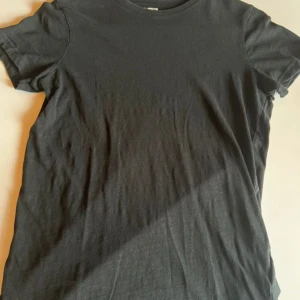 Svart basic t-shirt  - En svart, klassisk t-shirt från 157 med rund hals och korta ärmar. T-shirten är i mjuk bomull och har en enkel, stilren look utan tryck eller mönster. Perfekt att matcha med jeans eller shorts för en clean vibe.