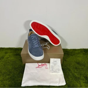 Christian Louboutin blå mockasneakers - Snygga blå sneakers från Christian Louboutin i mocka med klassisk röd sula och vita kanter. Skorna har rund tå, platt sula och snörning. Perfekta för dig som vill sticka ut med exklusiv stil och detaljer. Storlek 42. Hör av er vid frågor! Köpta för 456 euro (5037kr) mitt pris 2999kr! Dustabag, kvitto och annat og följer självklart med.