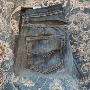 Levi's 501 mörkblå jeans straight fit - Klassiska Levi's 501 jeans i mörkblå tvätt med raka ben och femficksmodell. Snygga kontrastsömmar och ikonisk läderpatch bak i midjan. Jeansen är tillverkade i slitstarkt bomullsjeans och har en tidlös look som funkar till allt.