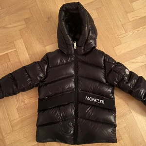 Svart pufferjacka från Moncler - Monclear Dunjacka, svart superfin till vardags och i skidbacken. Storlek 12 år 158/164. Jag är 160 cm lång och den är till och med lite stor. Motsvarar storlek 0 i vuxen storlek. Mycket bra skick! Jackan är äkta och fler bilder skickas till den intresserade!