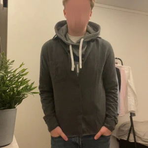 Mörkgrå långärmad kofta med knappar - Säljer en långärmad kofta från Dressman .Koftan har knäppning framtill, klassisk krage och en bröstficka. Perfekt för lager-på-lager och chill stil. Materialet är mjukt och känns skönt mot huden. Storlek cs