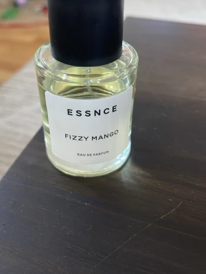 Essnce Fizzy Mango parfym - Eau de Parfum med namnet Fizzy Mango från Essnce. Perfekt för dig som vill sticka ut med en fräsch och modern doft. Flaskan har en stilren design som passar in i alla miljöer.