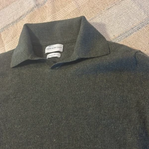 Grön merinoulltröja från These Glory Days - Snygg olivgrön polotröja från These Glory Days i mjuk merinoull. Tröjan har klassisk krage och lång ärm, perfekt för lager-på-lager. Enkel och stilren design som funkar till många olika looks. Storlek M men passar mer S jag är själv 174 och tycker att den är på gränsen till för liten.