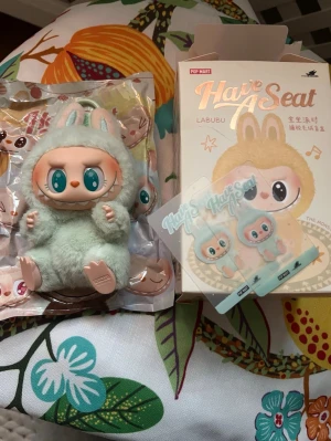 Mintgrön Labubu från Pop Mart - Specifikationer: Serie: The Monsters – Labubu Have a Seat (Ququ)  Typ: Pendant Figure  Storlek: ca 8 × 7 × 15 cm / 3,15 × 2,76 × 5,91 tum  Material:  Skal: 60% PVC, 40% Polyester  Stoppning: 70% Polyester, 20% ABS, 5% Järntråd, 5% Nylon  Tillverkare: POP MART
