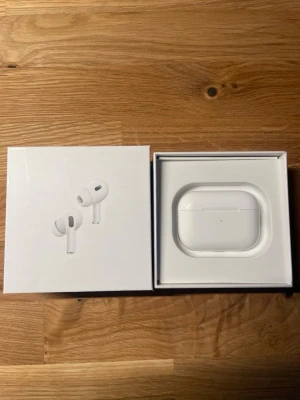 AirPods Pro Gen 2 2022 - Säljer ett par AirPods Pro från Apple i originalförpackning. Komplett med laddningskabel, extra öronkuddar och manualer. Produkten ser ut att vara i mycket gott skick utan synligt slitage. Perfekt för trådlös musik och samtal med aktiv brusreducering.