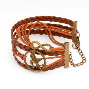 Fint inplastad hunger games ett Brun SNYGGT flätad läderarmband  med fågel väldigt bra skick.  - 🐦‍⬛Snyggt armband i brun flätad läderimitation med detaljer i antikguld, inklusive en fågel och en infinity-symbol. Justerbar kedja för perfekt passform. Perfekt accessoar för dig som gillar unika smycken och coola detaljer.🏹