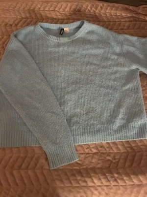 Ljusblå stickad tröja från H&M - Mysig ljusblå stickad tröja från H&M Divided i storlek M. Tröjan har rund halsringning, ribbade muddar vid ärmslut och nederkant samt långärmad passform. Perfekt för kyliga dagar och enkel att matcha med jeans eller kjol.