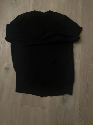 Svart stickad tröja i storlek S - En enkel mörk mörk blå stickad tröja i storlek S med rund hals och klassisk passform. Perfekt att matcha med jeans eller kjol för en clean look. Materialet är mjukt och bekvämt, och tröjan har långa ärmar. Snygg och stilren för dig som gillar basic.