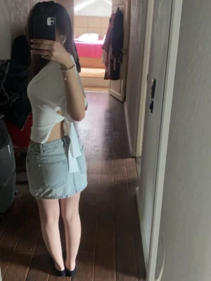 Vit t-shirt med knyt - Säljer en vit  t-shirt med snygg knytning i sidan och öppen rygg. T-shirten har korta ärmar och är gjord i mjukt bomullsmaterial. Köpt på Nelly.