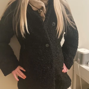 Svart teddyjacka från H&M - Mysig svart teddyjacka från H&M i storlek S. Jackan har en fluffig, krullig yta och stängs med stora svarta knappar framtill.. Fodrad insida så kan användas när det blir kallare. 