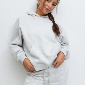 Ljusgrå hoodie med huva - Säljer en ljusgrå hoodie med huva och magficka. Tröjan har en relaxed passform, ribbade muddar vid ärmslut och nederkant samt långa ärmar. Perfekt för chill dagar och enkel att matcha med andra plagg.