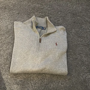 Grå stickad half zip från Polo Ralph Lauren - Säljer en grå stickad tröja från Polo Ralph Lauren i storlek M. Tröjan har half zip-dragkedja, ribbade muddar och klassisk broderad logga på bröstet. Perfekt för lager-på-lager och chillare dagar.