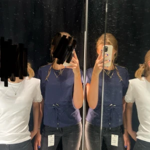 Marinblå topp med knyt i midjan från Zara - Säljer en marinblå topp med rund halsringning och korta ärmar. Toppen har ett snyggt knytband i midjan som ger en cool detalj och gör att passformen kan justeras. Perfekt till jeans eller kjol för en trendig look. Skriv om ni vill ha fler bilder!💗