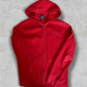 Röd hoodie från Polo Ralph Lauren S - Röd hoodie från Polo Ralph Lauren i storlek XL i barn men passar som S. Klassisk modell med huva, dragkedja framtill och två fickor. Broderad marinblå logga på bröstet. Tillverkad i mjuk bomull, perfekt för chill dagar eller när du vill ha en clean streetstyle. Skriv gärna med frågor eller funderingar!