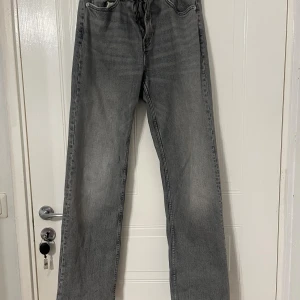 Grå raka jeans från Zara, strl 36 - Grå jeans från Zara i rak modell med klassisk femficksdesign. Jeansen har hög midja och raka ben, tillverkade i ett mjukt bomullstyg med lätt tvättad look. Perfekta för en avslappnad och trendig stil. Använd max 3-4 ggr.
