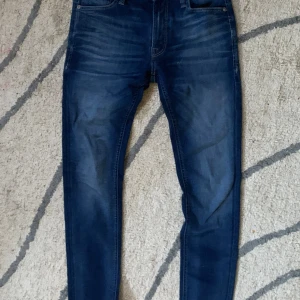 jeans från Jack & Jones - Snygga mörkblå skinny jeans från Jack & Jones med klassisk femficksdesign och diskreta slitningar. Jeansen har normal midja och smal passform hela vägen ner. Perfekta för dig som gillar en tajt look och vill ha ett par stilrena jeans i garderoben.