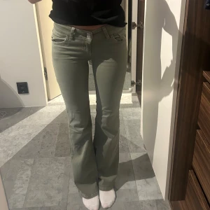 Olivgröna bootcut jeans - Snygga olivgröna jeans med bootcut-modell och låg midja. Byxorna har klassiska fem fickor och är tillverkade i ett stretchigt bomullsmaterial som sitter skönt. Perfekta för dig som gillar en avslappnad men trendig look.