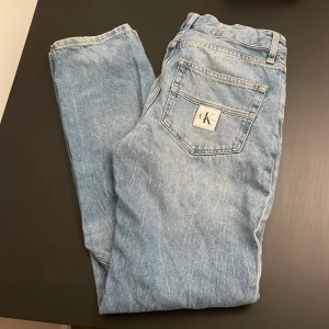 Ljusblå jeans från Calvin Klein - Säljer ett par ljusblå jeans från Calvin Klein som är storlek 16 vilket passar om du är runt 175 och CK-logga på bakfickan. Jeansen har raka ben och normal passform, tillverkade i mjukt bomullsjeans. Perfekta för en avslappnad och stilren look.