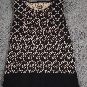 LYX! Wolford Aurora Monogram Crop Top Svart/Beige - Nyskick Strl L - Säljer en vacker, exklusiv Wolford Aurora Monogram Crop Top i storlek Large (L). Toppen är stickad i ett sömlöst material som har Wolford-loggor och mönster i jacquardstickning.  Denna topp är perfekt för att bära på gymmet, som en snygg sommartopp, eller under en kavaj för en chic look.