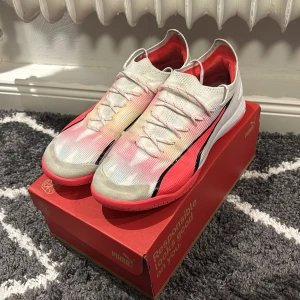 Puma inomhusskot - Säljer ett par Puma fotbollsskor i storlek 42.5. Skorna har en vit ovandel med röda och svarta detaljer, samt en röd sula. Skorna är lite skadade men funkar bra.