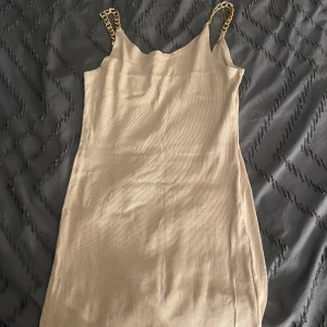 Beige kort klänning - En beige kort klänning perfekt för sommaren när man vill gå runt i något enkelt men även snyggt med kedjeband över axlarna
