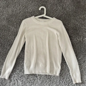 Vit stickad tröja från Vila - En stilren vit stickad tröja från Vila i storlek XS. Tröjan har rund halsringning, ribbade muddar och är långärmad. Perfekt att matcha med jeans eller kjol för en clean och enkel look.