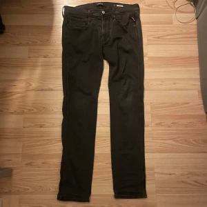 Svarta Replay jeans slim fit 32/32 - Svarta jeans från Replay i modellen slim fit, storlek 32/32. Klassisk femficksdesign med dragkedja och knapp framtill. Jeansen har en stilren look och är tillverkade i ett mjukt och stretchigt bomullsmaterial för skön passform.