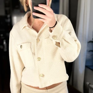 Krämvit cardigan jacka från Zara - Perfekt höstjacka!!🍁Säljer en krämvit cardigan jacka från Zara med snygg struktur och guldiga knappar. Jackan har två stora bröstfickor, klassisk krage och är tillverkad i ett mjukt, vävt material. Perfekt för dig som gillar stilrena och trendiga plagg.