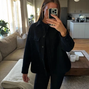 Svart overshirt från Zara, S - Svart overshirt från Zara med klassisk krage och två stora bröstfickor med knappar. Jackan har en loose passform och är tillverkad i ett tjockare ullmaterial som ger en cool och avslappnad vibe. 