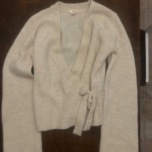 Beige omlottkofta från Gina Tricot - Supermjuk beige omlottkofta från Gina Tricot med knyt i sidan. I nyskick och finns i butik för 399:-. Storlek 158-164