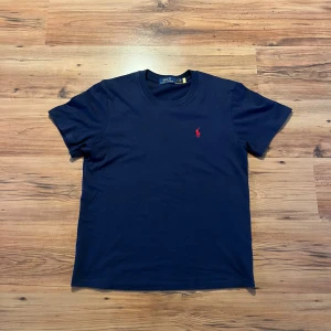 Mörkblå t-shirt från Polo Ralph Lauren - Mörkblå polo Ralph lauren tröja size S 👕                      - längd (64cm), bredd (47cm), ärm (20cm)         - 10/10 skick, inga defekter, använd en gång    Hör av er 🫡